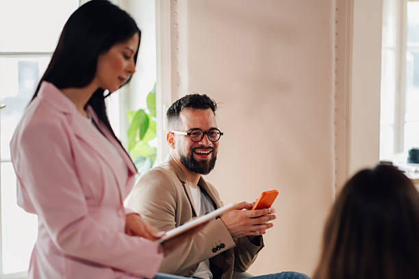 istock Smiling businessman using smartphone during meeting with colleagues 2213064303