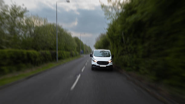 istock White Van Driving on Rural Road Under Cloudy Sky 2213072735