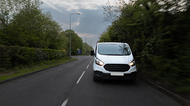 istock White Van Driving on Rural Road Under Cloudy Sky 2213072746