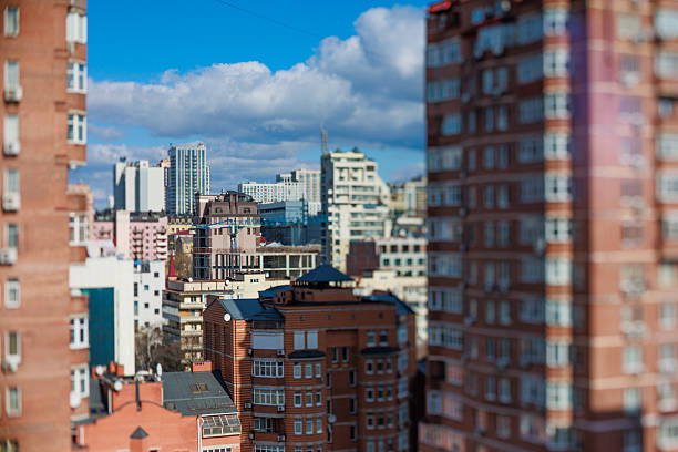 Striking tilt-shift cityscape featuring a mix of modern and older architecture under a bright blue sky, creating a captivating miniature model effect