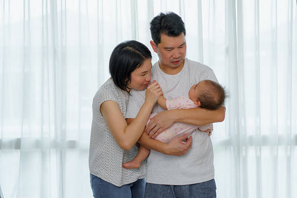 gentle moment as father cradles his sleeping baby in pink, radiating warmth, security, and affection in a cozy indoor setting.