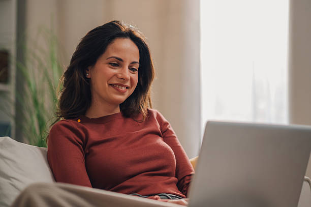 istock Young woman relaxing on sofa using laptop at home 2213080635