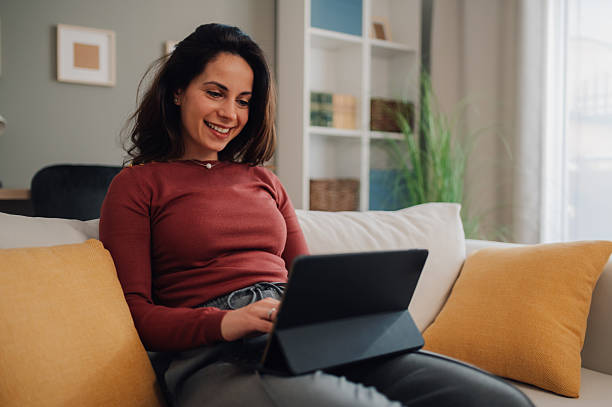 istock Young woman working remotely from home using digital tablet on sofa 2213080712