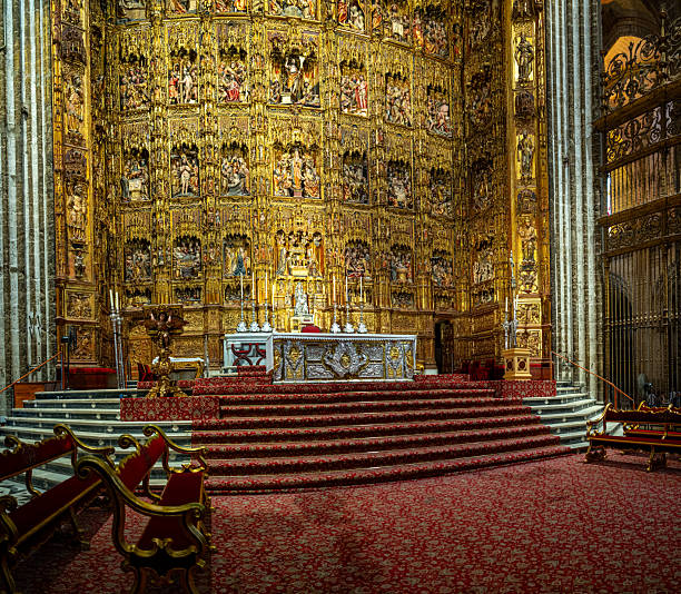 Parroquia de San Gines, Lanzarote, Canary Islands, Spain - March 1st 2025:  his image captures the grandeur of a Catholic church's main altar, richly adorned with religious statues, intricate architectural details, and symbolic elements. At the center stands a crucifix, flanked by statues of saints positioned within red niches, adding depth to the composition. The surrounding wooden arches, columns, and ceiling contribute to the historic and ornate ambiance, reflecting the deep religious significance of the altar as the focal point of worship.