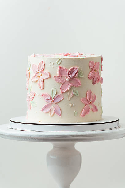 Birthday, wedding or anniversary cake with white cream cheese frosting and decorated with pink cream flower petals. White background