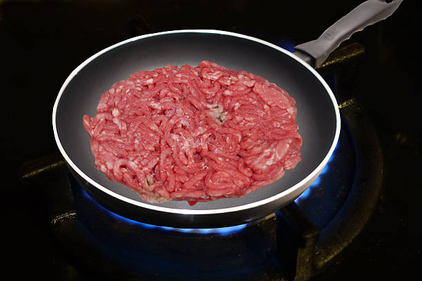 Browned minced steak being cooked in a frying pan on a gas hob