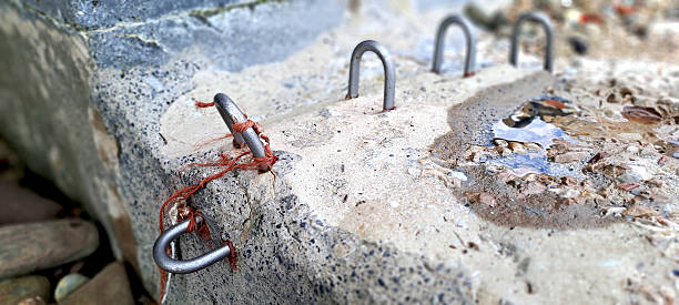 Close-up of metal handles embedded in a concrete block, with orange string wrapped around one of them