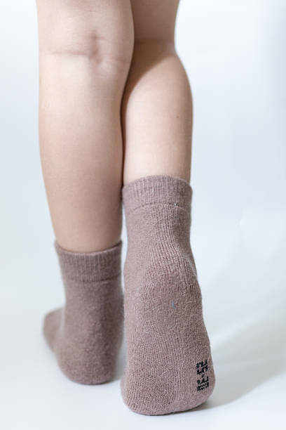 istock Baby feet in warm brown socks on a white background 2213099511