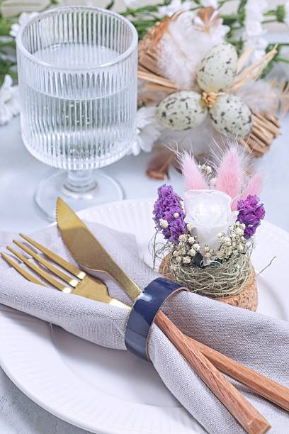 istock Easter table setting decorated with flower arrangement and golden cutlery, vertical 2213099758
