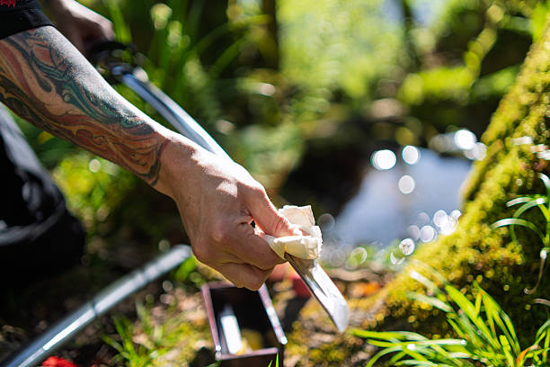Skilled practitioner carefully wiping traditional japanese katana sword, maintaining blade in serene outdoor environment