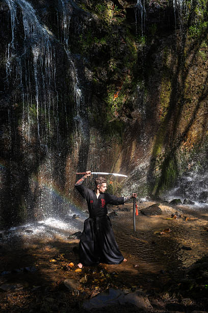 Male practitioner performing iaido, wielding katana near cascading waterfall, embodying traditional japanese martial arts discipline and grace