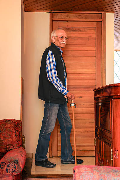 Full length portrait of a senior man standing with a walking cane in a park