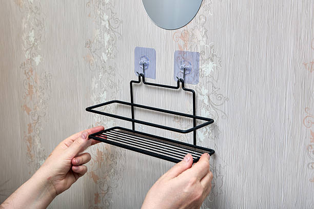 istock Wire bathroom shelf is being hooked onto two transparent nano adhesive hooks on wall offering quick and tool-free installation for bathroom storage. 2213107983