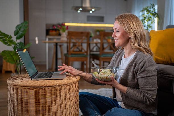 istock Woman working from home and eating a salad while using laptop 2213109761