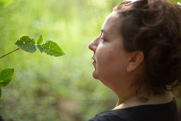 Woman admiring the beauty of a leaf in a forest, enjoying the nature