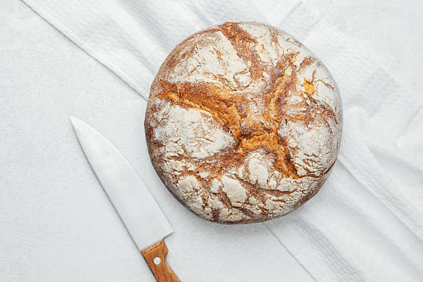 istock Freshly baked round bread with a knife on a kitchen countertop 2213122821