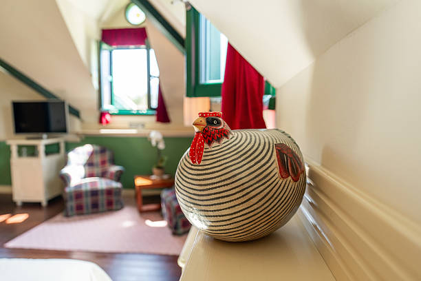 Elegant vase adorns a sunlit ledge in a cozy hotel room, with gabled windows, classic furnishings, and a serene color palette capturing the essence of vintage charm.