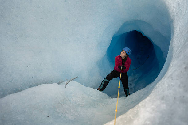 istock Female explorer climbing in a glacier cave using rope and ice axe 2213133199