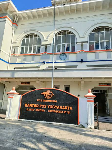 Yogyakarta, Indonesia -  April, 2025 :   the iconic Kantor Pos Yogyakarta (Yogyakarta Main Post Office), a colonial-style building located on Jalan Panembahan Senopati. The structure stands out with its white facade, large arched windows, and a clock mounted on the upper wall. In front of the building, there's a café called 
