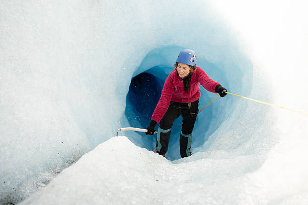 istock Female tourist exploring a deep blue ice cave in a glacier 2213134739
