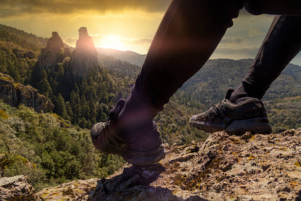 Climber takes a break on the edge of a cliff while enjoying the sunset over the mountains in mineral del chico national park