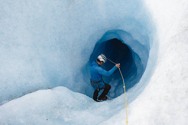 istock Mountain guide exploring a glacier crevasse with rope and crampons 2213137919