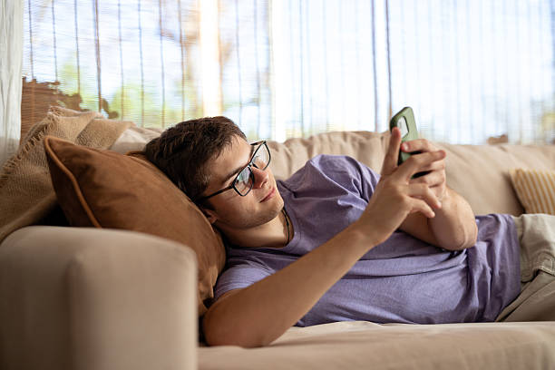 istock Young man using his smartphone in the living room 2213138063