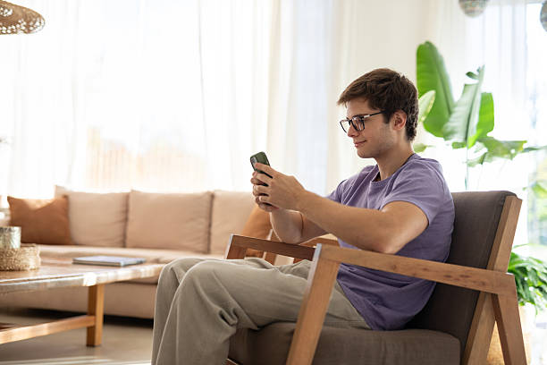 istock Young man using his smartphone in the living room 2213138212