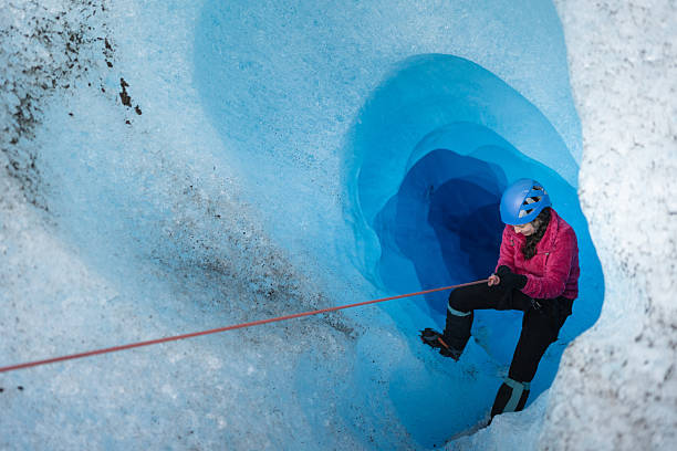 istock Female explorer descending into a blue glacier crevasse 2213139012