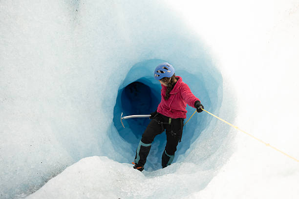 istock Female climber exploring a deep blue glacial crevasse 2213139110