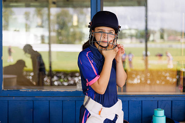 Young female cricket player putting her helmet on