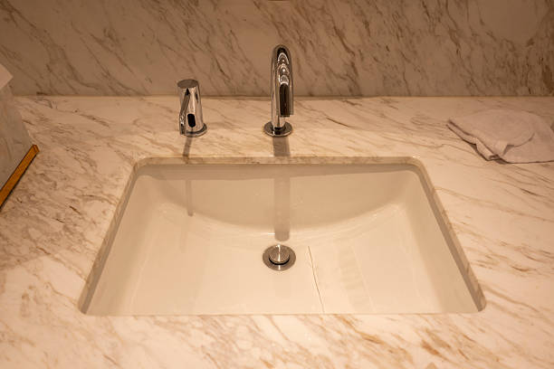 A sleek, modern bathroom sink set into a marble countertop, featuring chrome fixtures. The clean lines and minimalist design convey elegance and sophistication, suitable for high-end interior design projects or home decor inspiration.