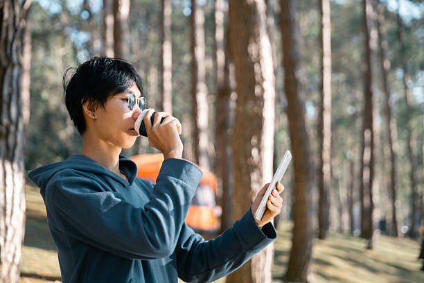 istock Remote work technology online close up communication smart phone laptop telephone digital travel brown nature sunlight camp beverage morning sit drink coffee tent orange outlying concept background. 2213150723