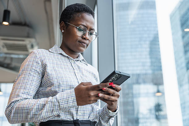 Serious Professional Woman Checking Phone in Modern Office Environment