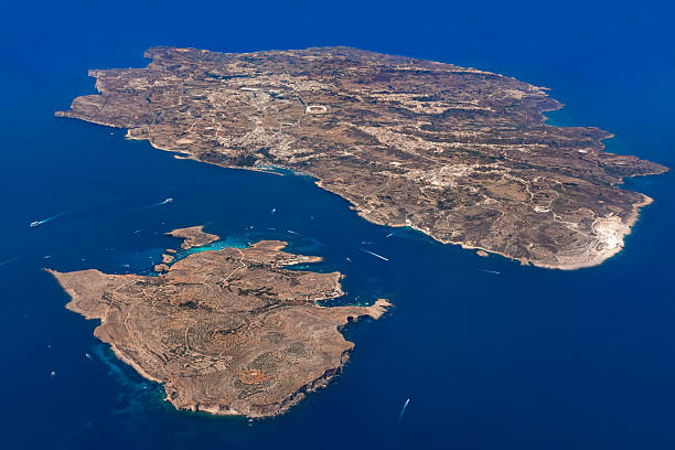 Golden islands of Gozo and Comino float in sapphire Mediterranean waters, their rugged coastlines and turquoise coves alive with boats and sunlit serenity.