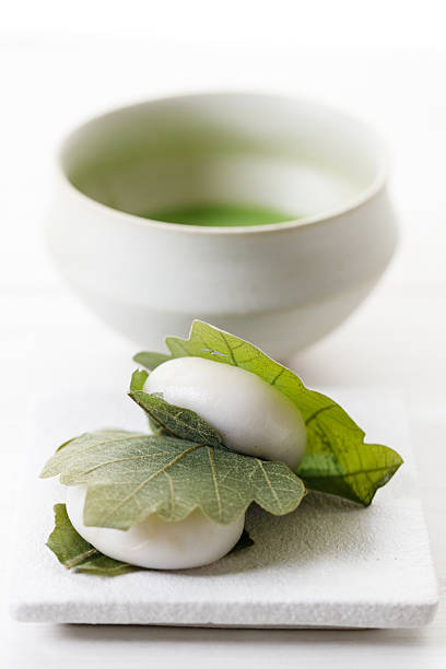 Kashiwa mochi and Cup of fresh matcha tea. Japanese sweet from mochi or rice cake and sweet red bean paste filling surrounded with Kashiwa or Oak leaf . Kashiwa mochi and Cup of fresh matcha tea. Japanese sweet from mochi or rice cake and sweet red bean paste filling surrounded with Kashiwa or Oak leaf . Selective focus. red bean dessert stock pictures, royalty-free photos & images