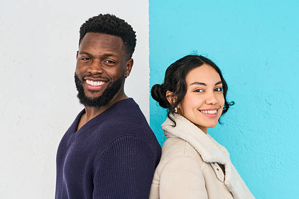 istock Happy multi ethnic couple smiling, standing back to back against colorful background 2213164117