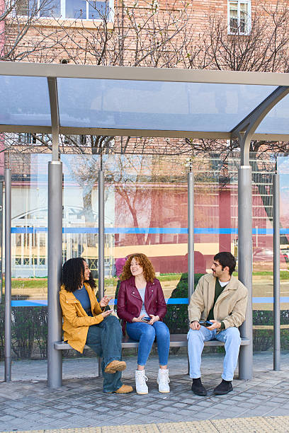istock Students chatting and using their smartphones while waiting at the bus stop 2213164608