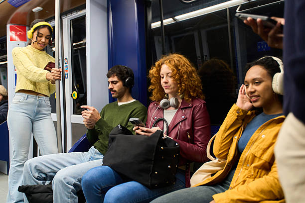 istock Young people using smartphones and headphones on subway train 2213165805