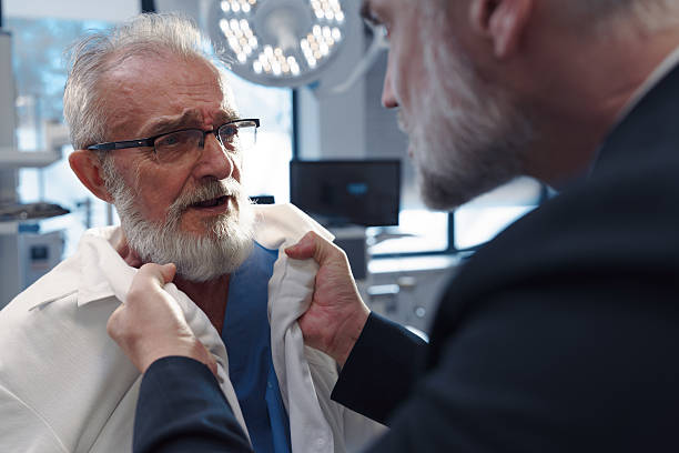 Aggressive man have conflict with doctor, holding him by coat. stock photo