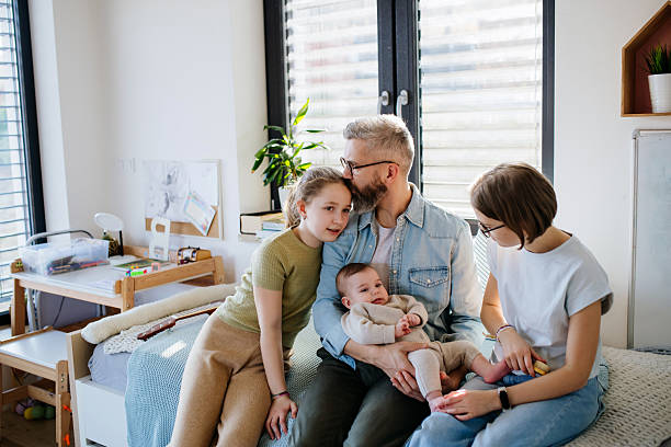 istock Three sisters looking at newborn brother in fathers arms. 2213169451