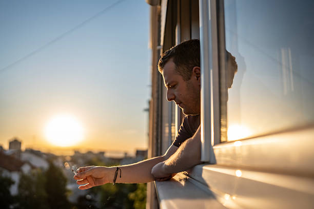 istock Man Reflecting by a Window During a Beautiful Sunset Overlooking the Cityscape 2213170207