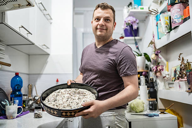 Person presenting a freshly prepared cake in an organized home kitchen. Highlights domestic life, culinary creativity, and enjoyment of cooking. Positive and cheerful ambiance captured in a casual setting.