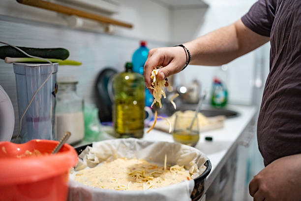 istock Person Sprinkling Cheese While Preparing Homemade Pizza in a Cozy Kitchen Setup 2213170247