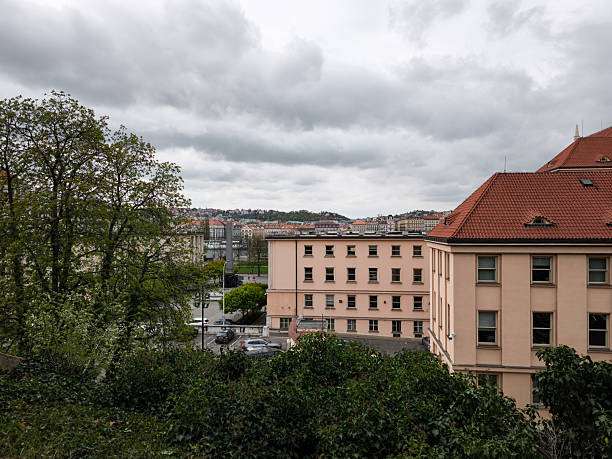 Prague, Czech republic - April 15, 2025: Residential buildings and trees lining the streets under a dramatic, cloudy sky in prague, czech republic, create a picturesque urban scene