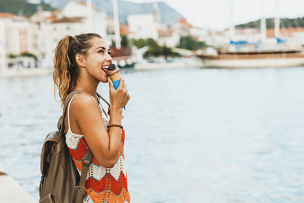 Attractive young woman enjoying an ice cream while exploring the wonderful seaside of Mediterranean.