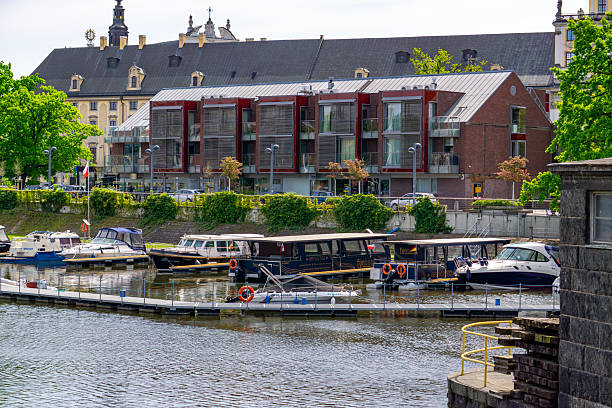 Wrocław, Lower Silesia Voivodeship, Poland - April 29, 2025 A view of the marina on the Odra River in Wrocław, with moored tourist boats and motorboats. In the background, you can see modern apartment buildings and the historic building of the University of Wrocław with Baroque architectural details. A Polish flag flutters on the mast of one of the boats