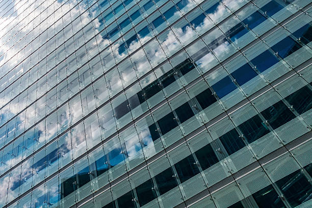 istock Abstract facade of tall glass office building under cloudy sky with reflections 2213172974