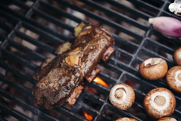 istock Grilling beef ribs and mushrooms on barbecue grill. 2213178038
