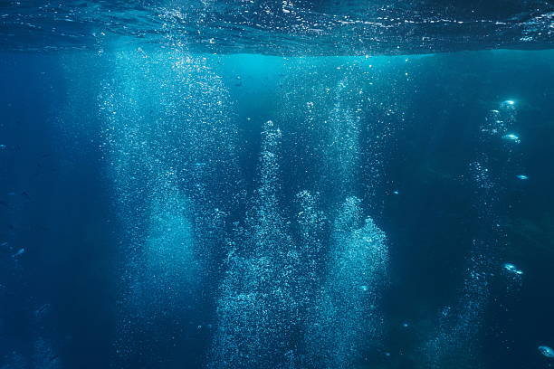 Air bubbles rising to the surface with light rays from scuba diving in the ocean.